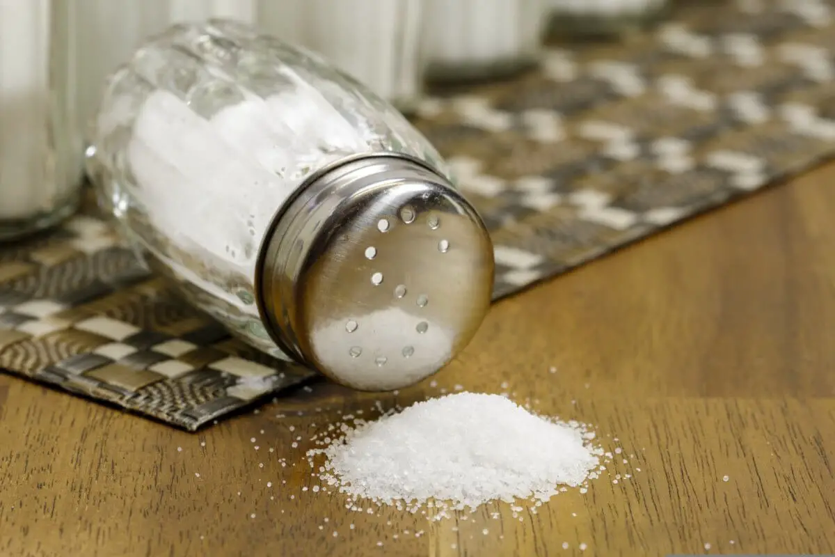 Salt shaker with salt spilled on the table