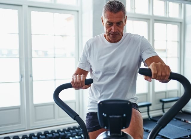 mature man doing HIIT workout to slow aging on stationary bike