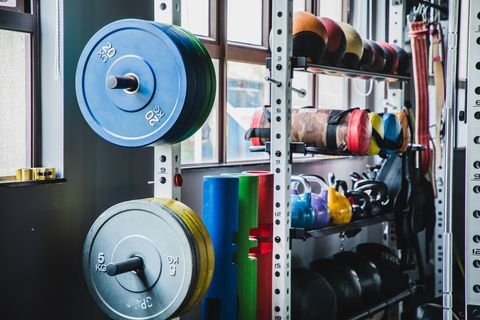 medicine balls, kettlebells and a variety of weight training equipment on a rack