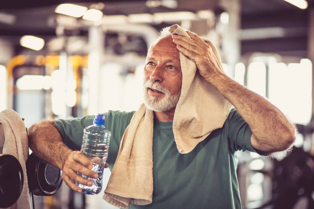 Older man wiping sweat from an intense workout in the gym.