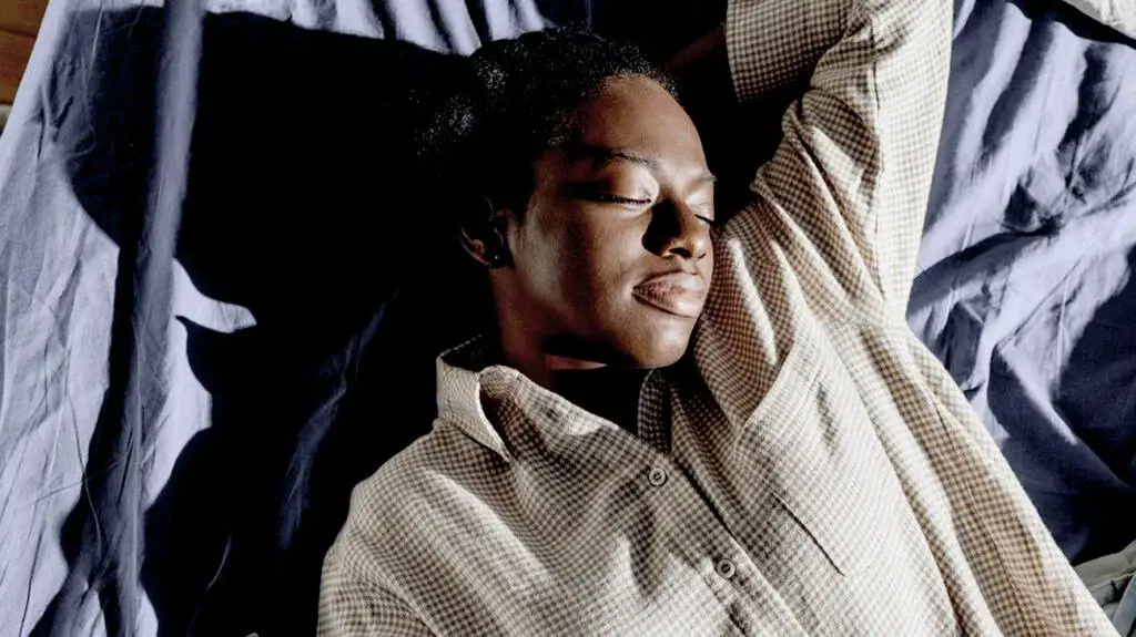 black person in brown checkered pajamas asleep on bed