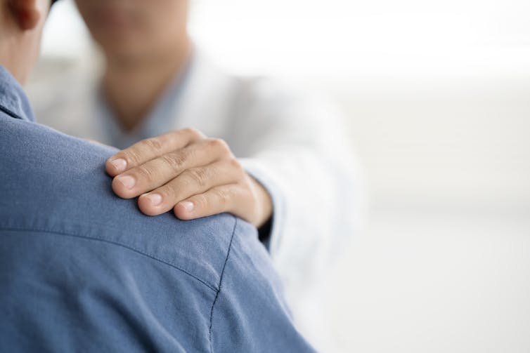 Doctor in white coat putting hand on patient's shoulder