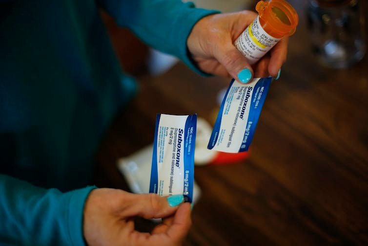 Close-up photo of a woman's hands holding two small packets labeled Suboxone.